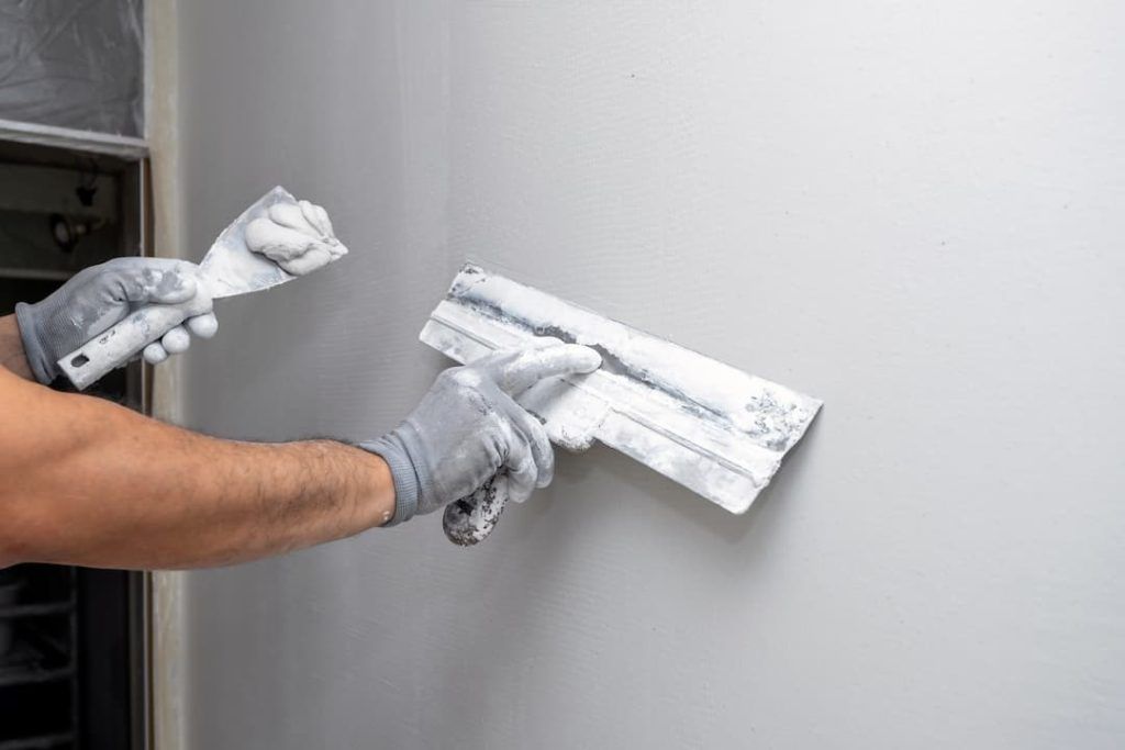 a person painting a wall with a spatula